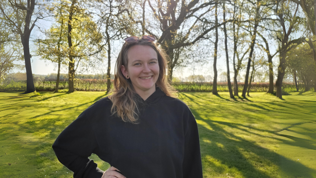 Die Bloggerin Juliane Kau steht lachend mit einer Sonnenbrille in den Haaren im Garten. Es sind Bäume und ganz viel Rasen zu sehen. Die Sonne scheint.