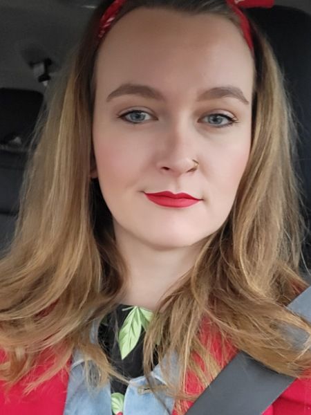 Die Bloggerin Juliane Kau ist zu sehen. Sie trägt zur Veranstaltung "Harry Potter in concert" roten Lippenstift, ein rotes Haarband und einen passenden roten Mantel. Das Bild wurde im Auto aufgenommen. 